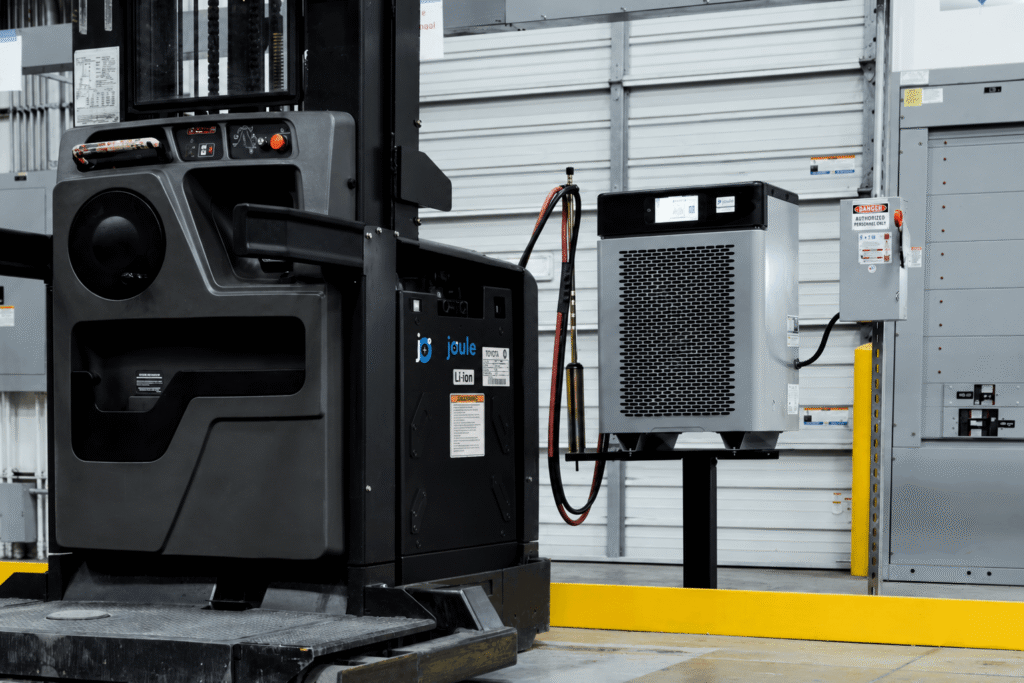 Forklift with Joule Li-ion battery pack beside an industrial charging station in a warehouse